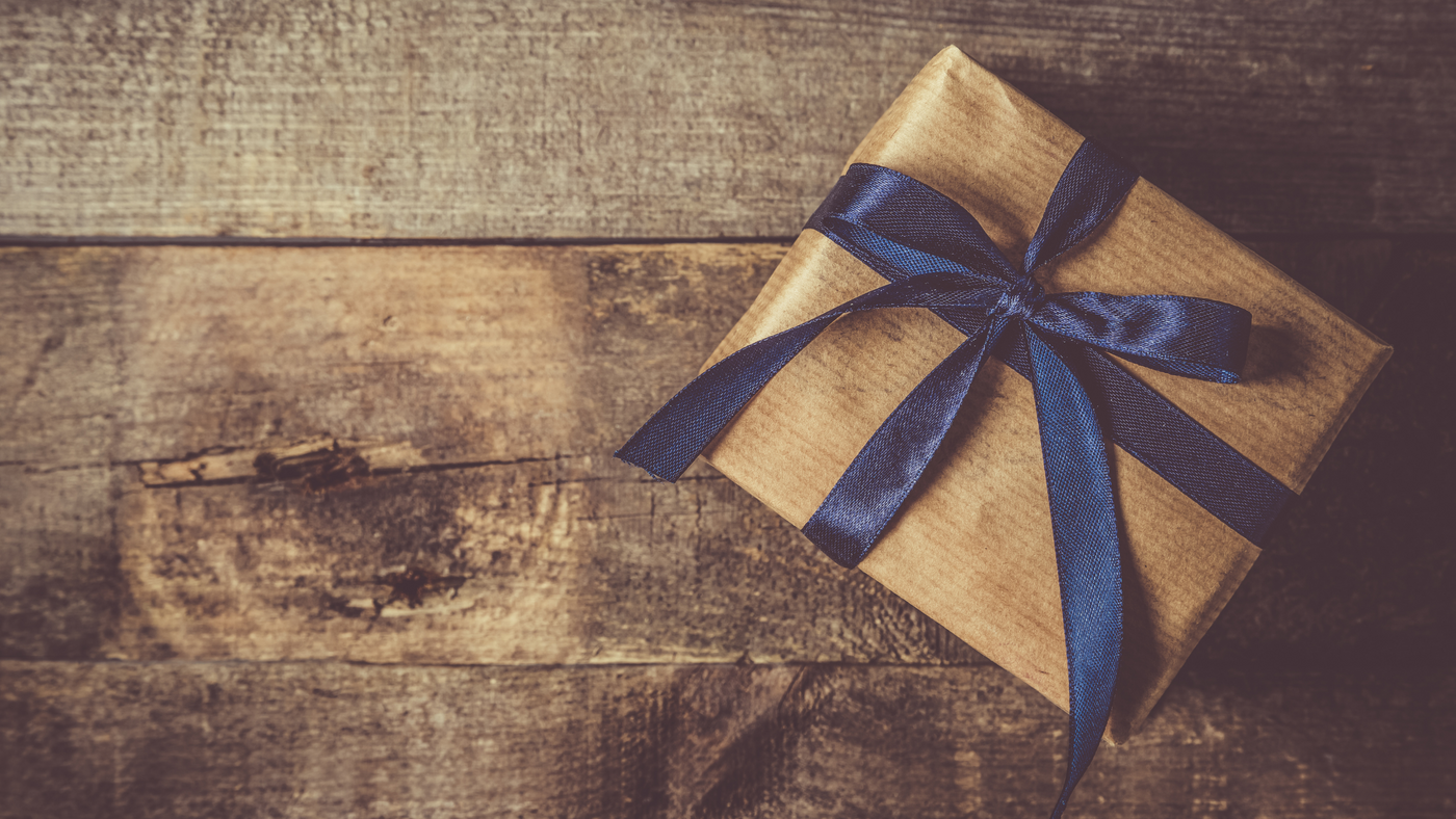 brown paper gift wrapped on wooden floor and finished with blue bow
