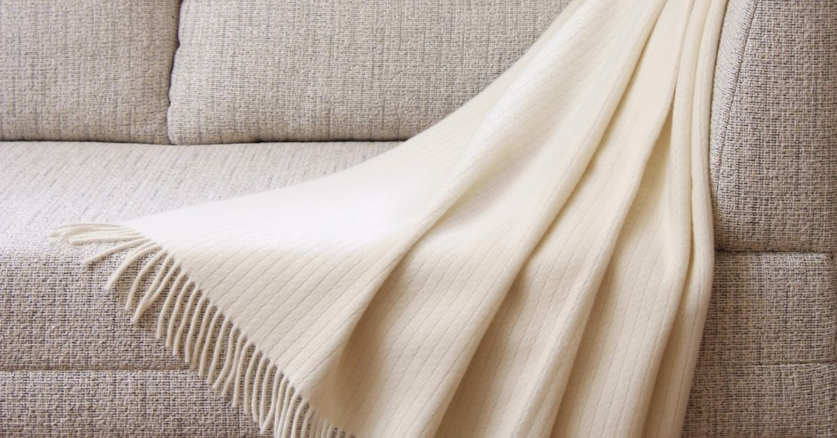white fleecy blanket draped over taupe coloured textured sofa 