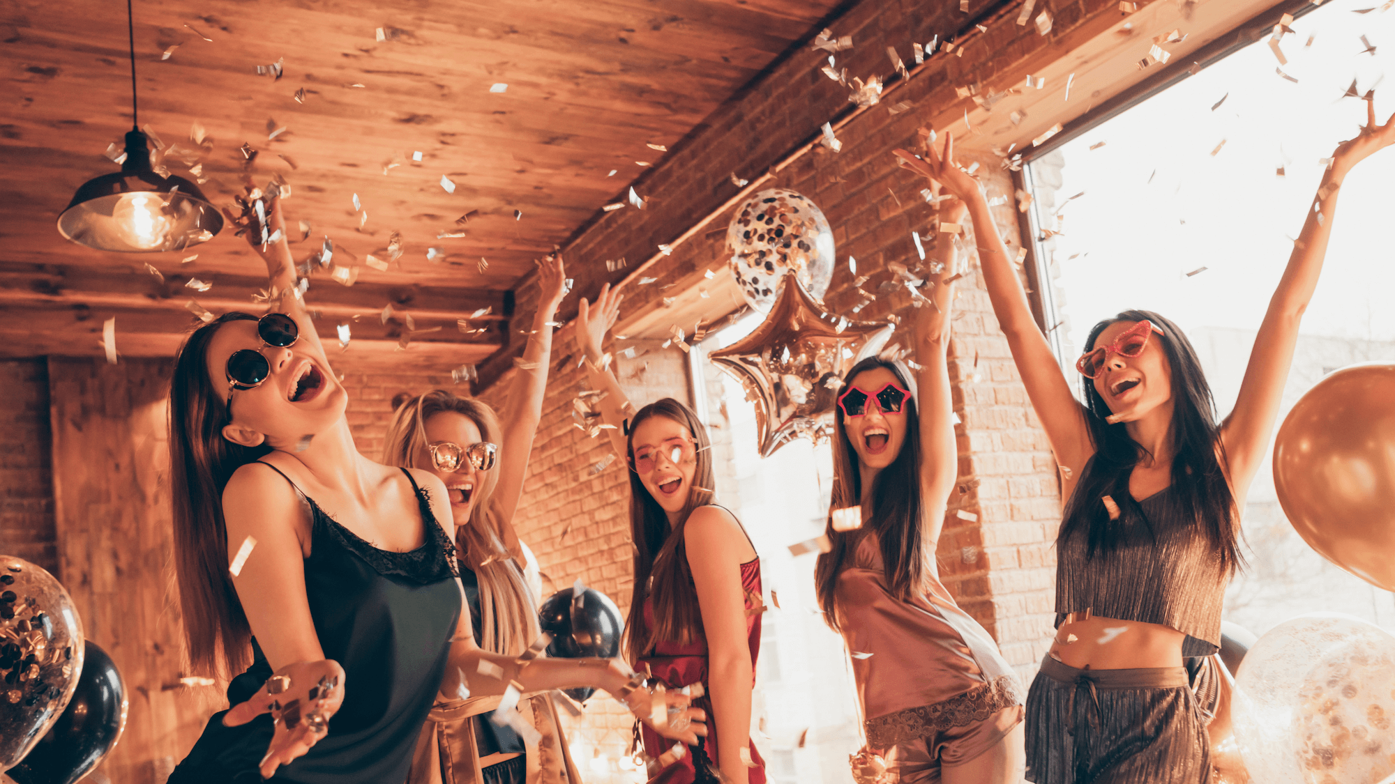group of young girls dancing in house celebrating with gold balloons and confetti wearing novelty sunglasses bridal party hen night