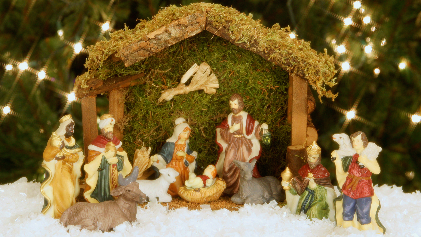 christmas nativity set on snow with christmas tree in the background