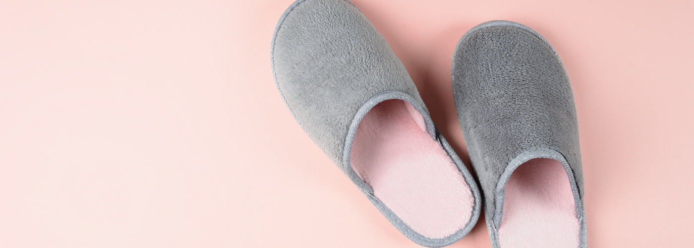 a pair of grey mule slippers on a pink background