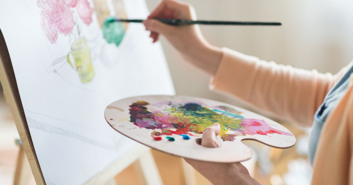 person holding paint tray creating a watercolour canvas art piece