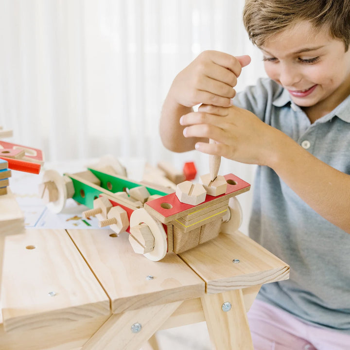 Boy playing with a wooden screwdriver to make a wooden car