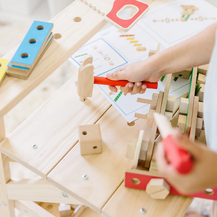 Child playing with a wooden hammer on a workbench toy