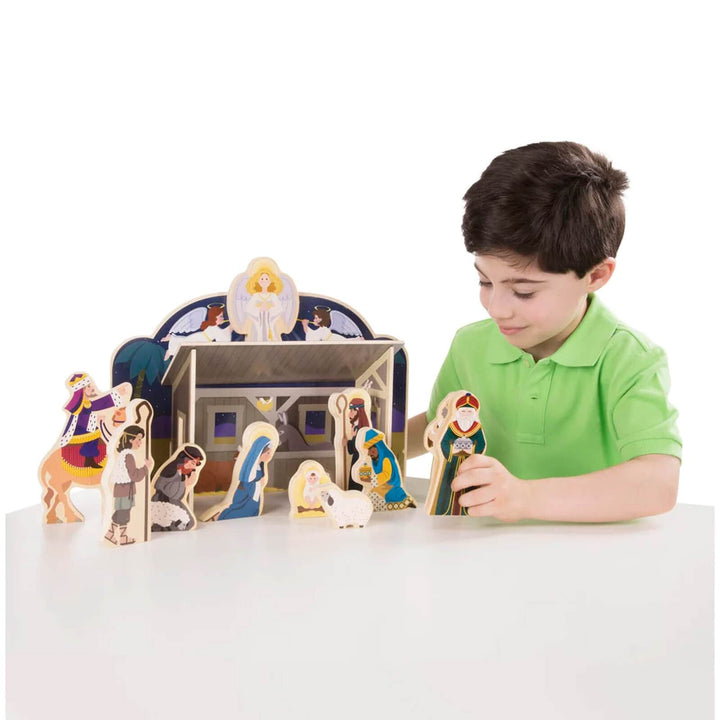 Boy playing with a wooden Christmas nativity ser