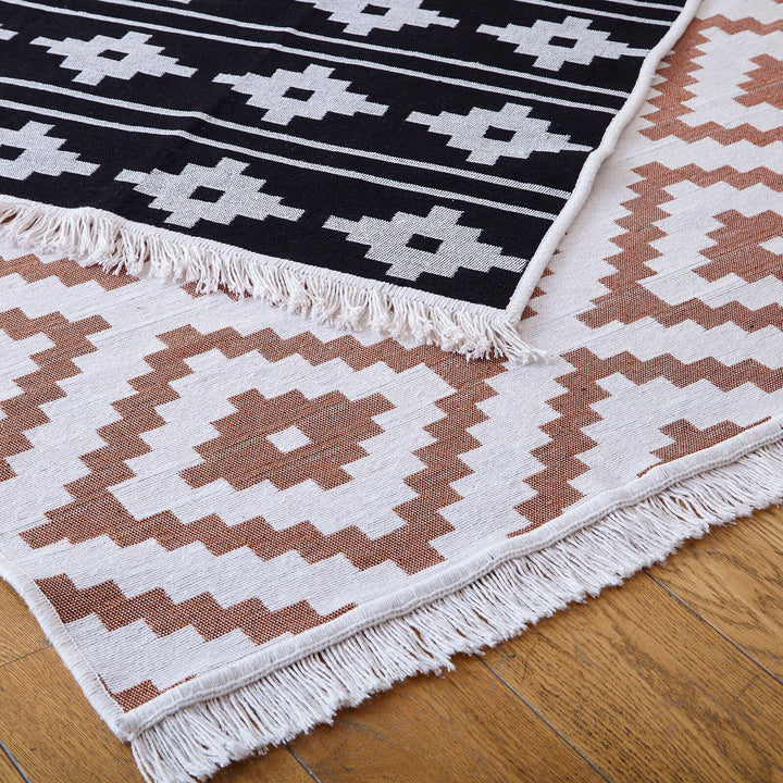 Brown and white aztec style pattern reversible rug with black and white back