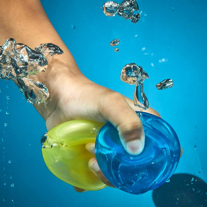 Hand under water refilling a yellow and a blue Nerf Hydro Ball