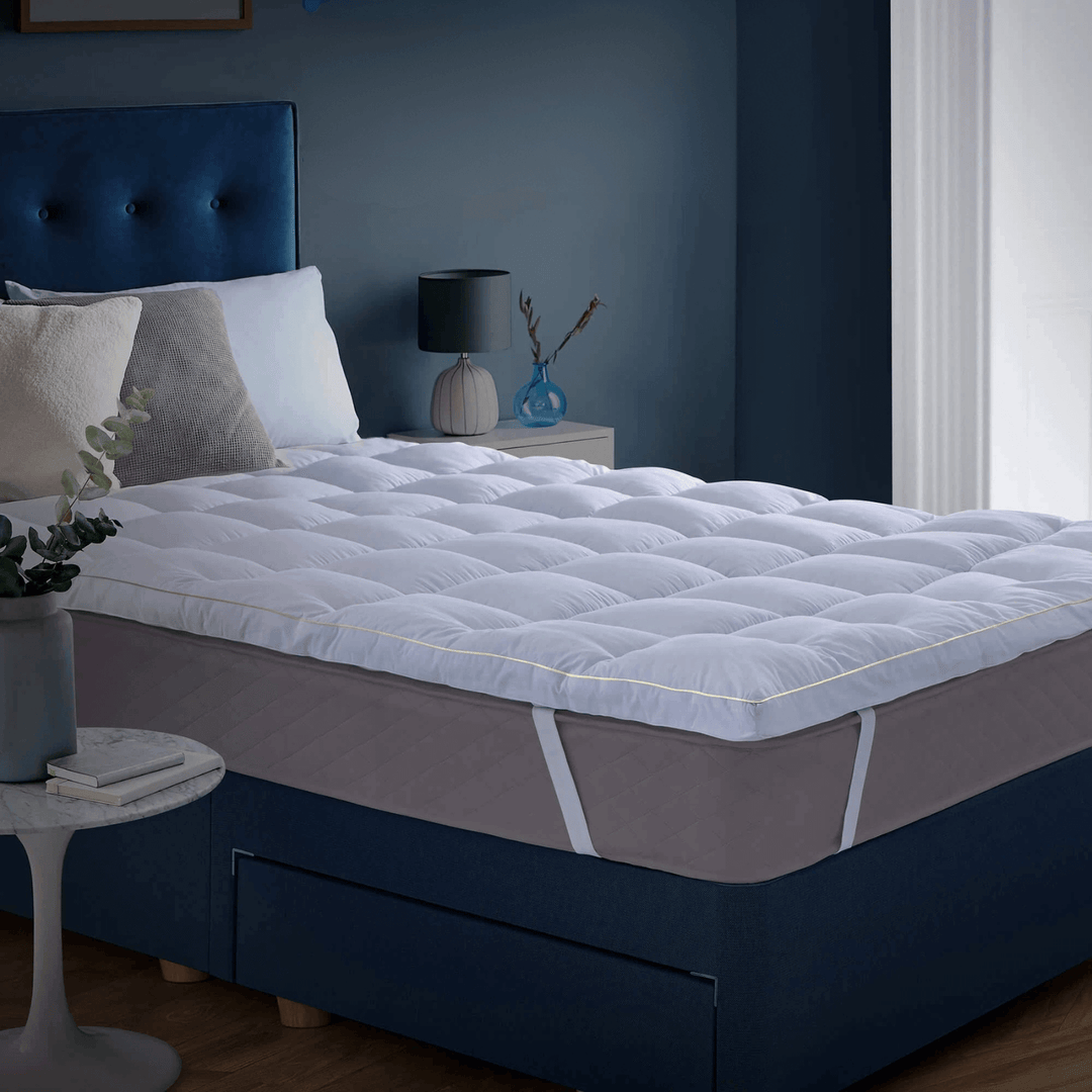 Mattress topper on a bed in a bedroom setting with blue walls and decor.