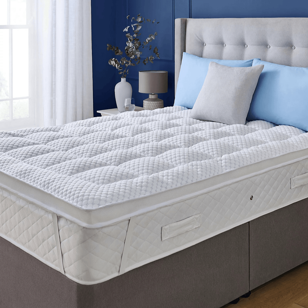 Mattress topper on a bed with blue and white pillows in a bedroom setting.