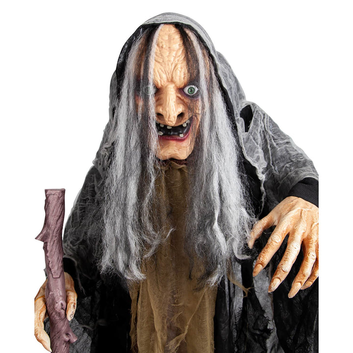 Close up of an old witch halloween decoration with long grey hair and walking stick