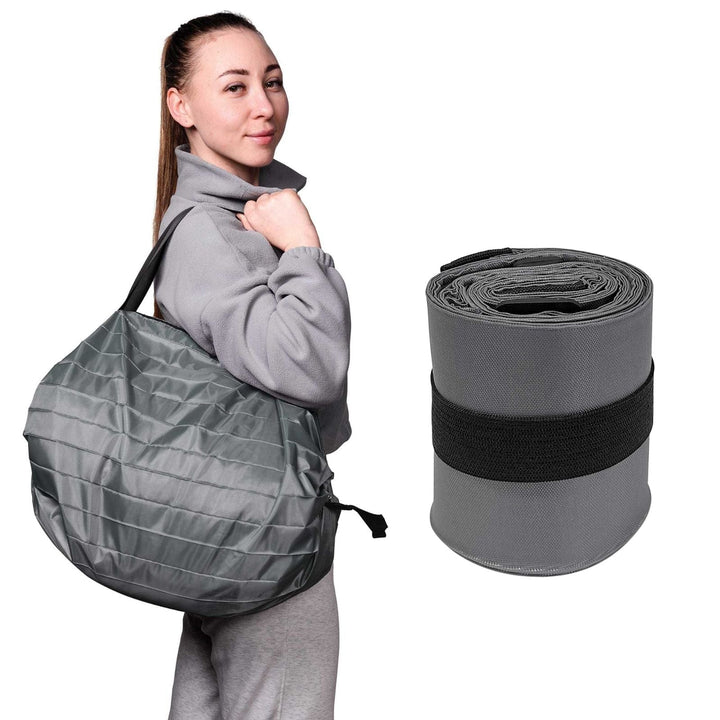 Woman holding a gray quilted bag with a rolled-up gray bag to the side on a white background