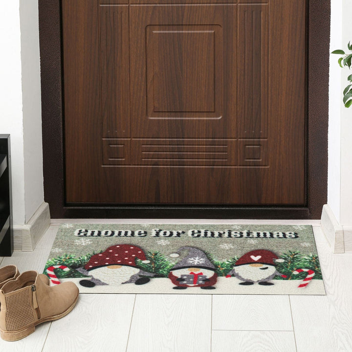 Decorative doormat with Christmas-themed gnomes in front of a wooden door.