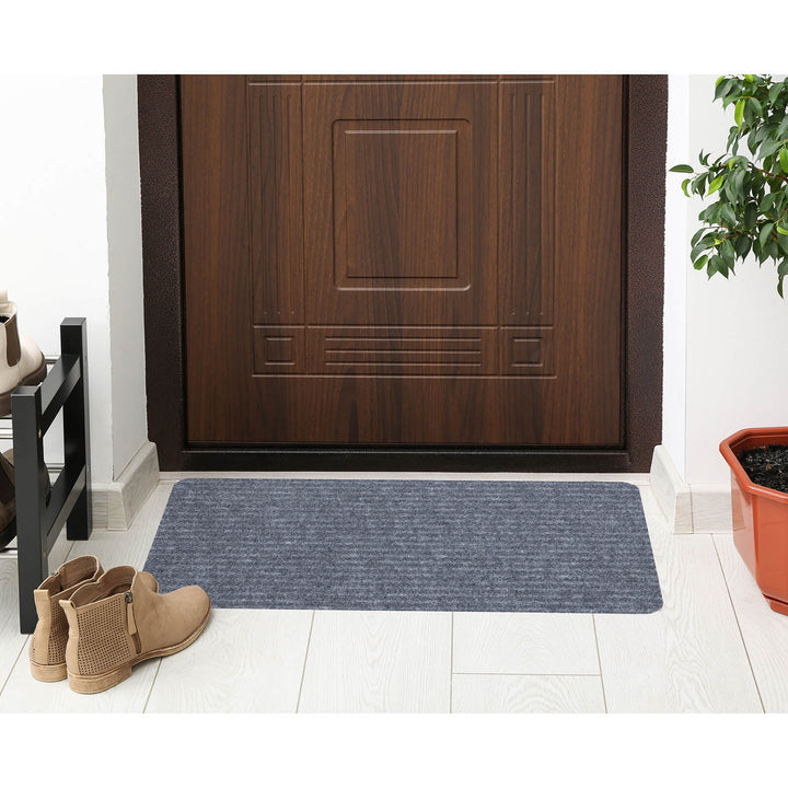 Grey ridged door mat on the floor with plant and boots