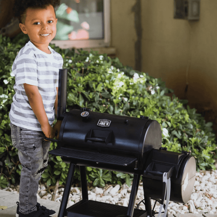 young boy smiles as he pushes pretend toy smoker in the garden