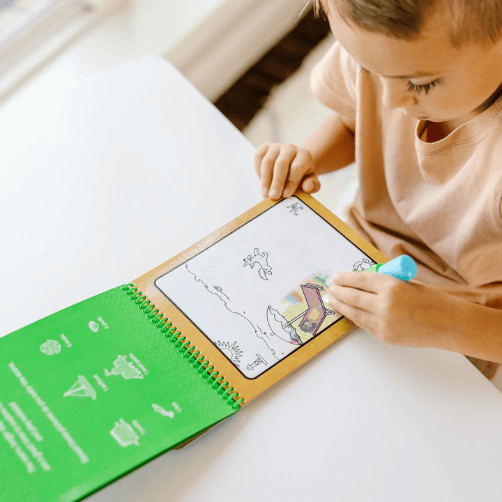 little boy uses water refill pen to colour summer beach scene at home