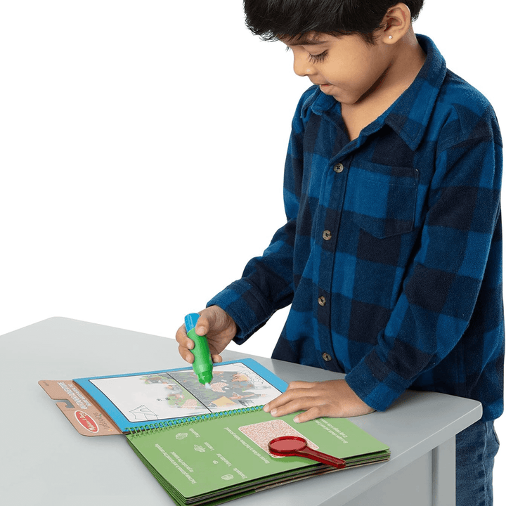 little boy uses chunky water filled pen to colour outdoor scenes inside the activity book