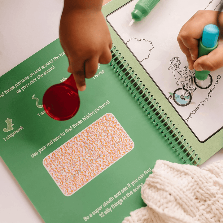 2 little hands use pen to colour in water pad with red lens to highlight additional puzzles