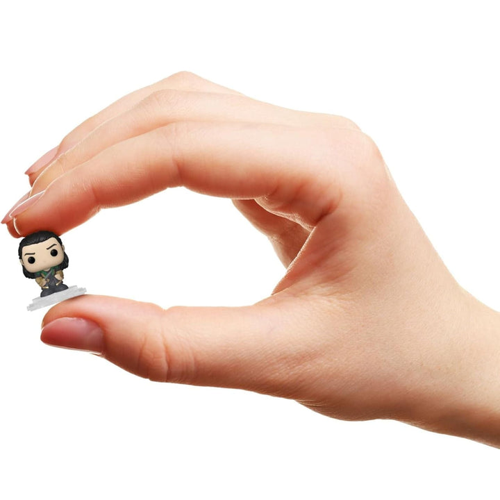 Hand holding a small Loki figurine against a white background