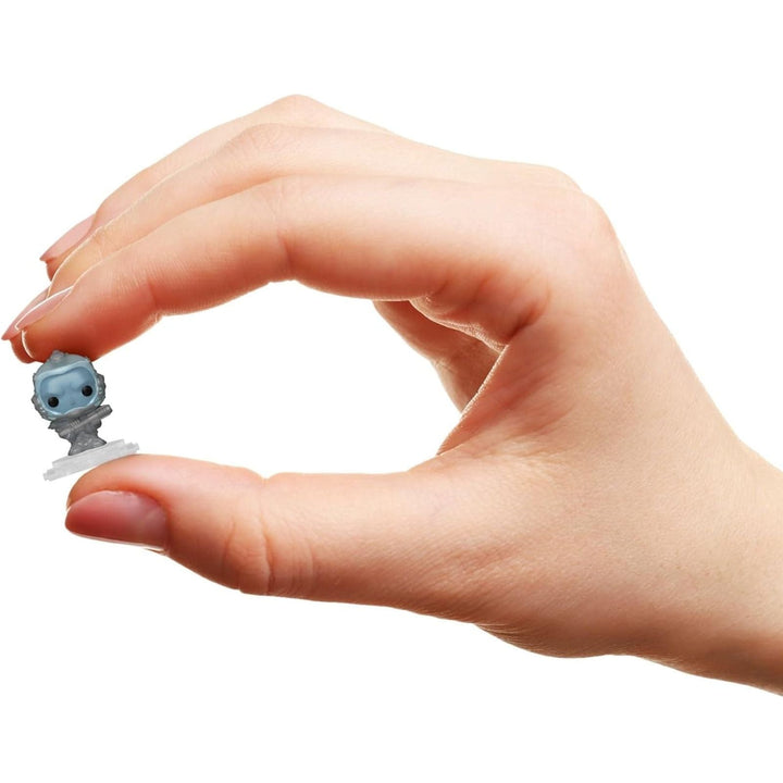 Hand holding a small mr freeze figurine against a white background