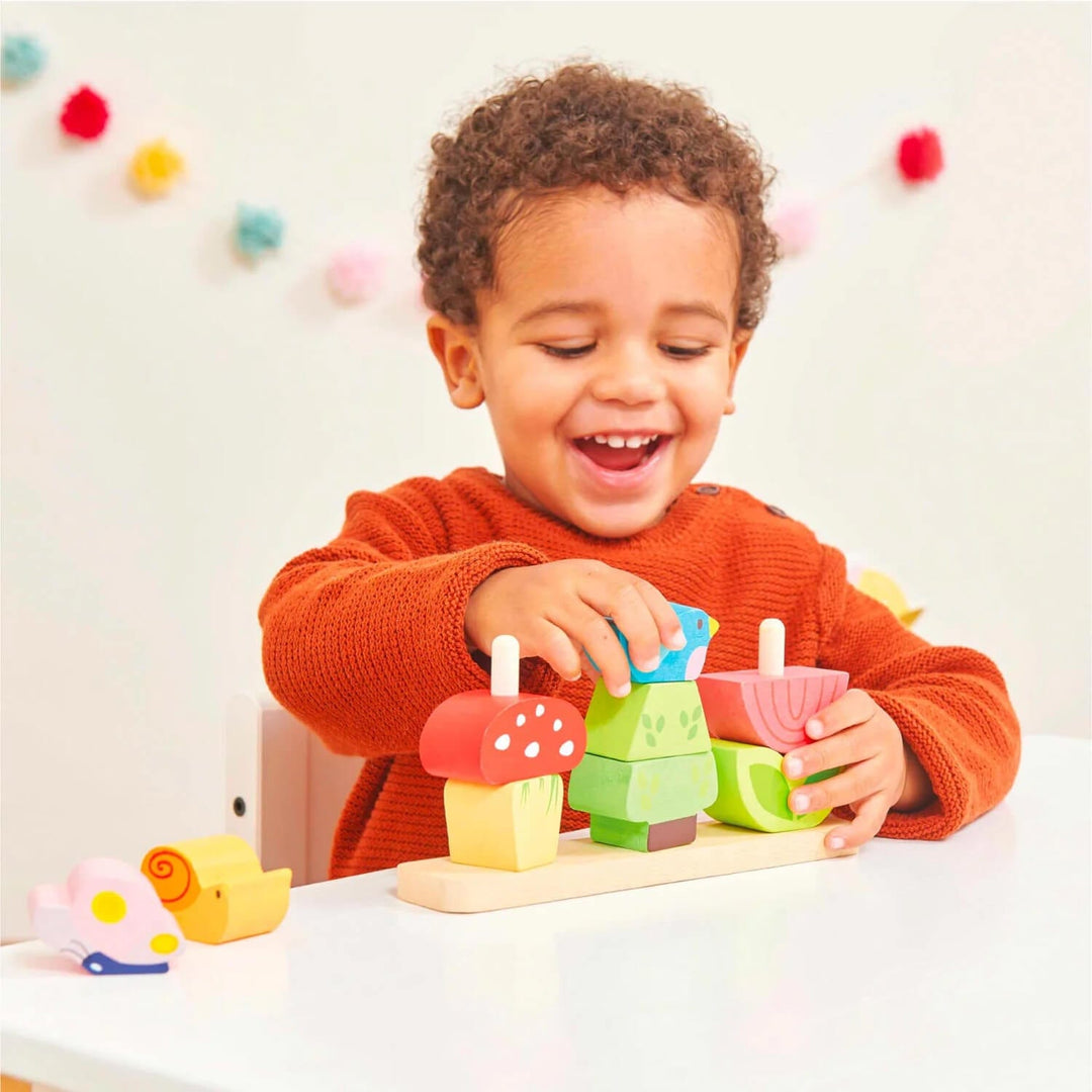 Child playing with colourful wooden stacker toy on a table with a light background