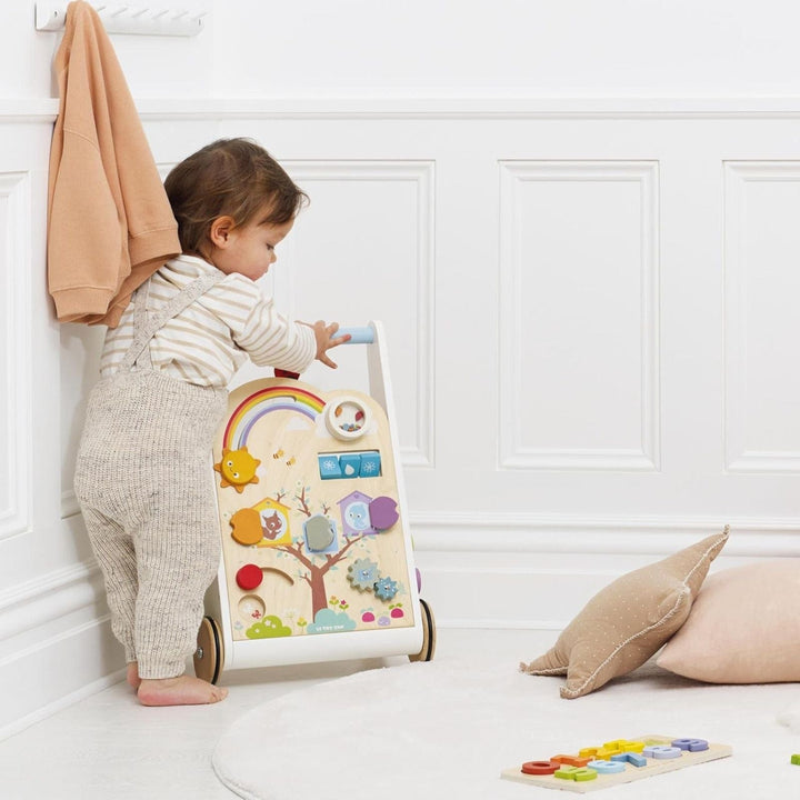 small baby leans on baby walker as he learns to walk