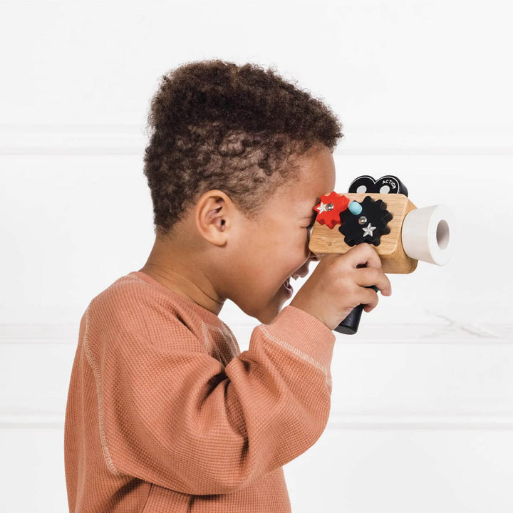 Child playing with a toy camera against a white background