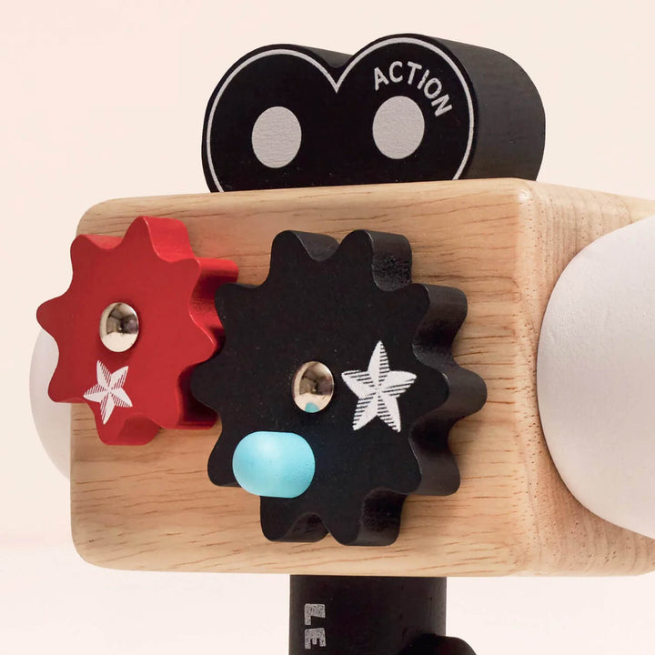 Toy Hollywood camera with gears and a wooden base on a light pink background