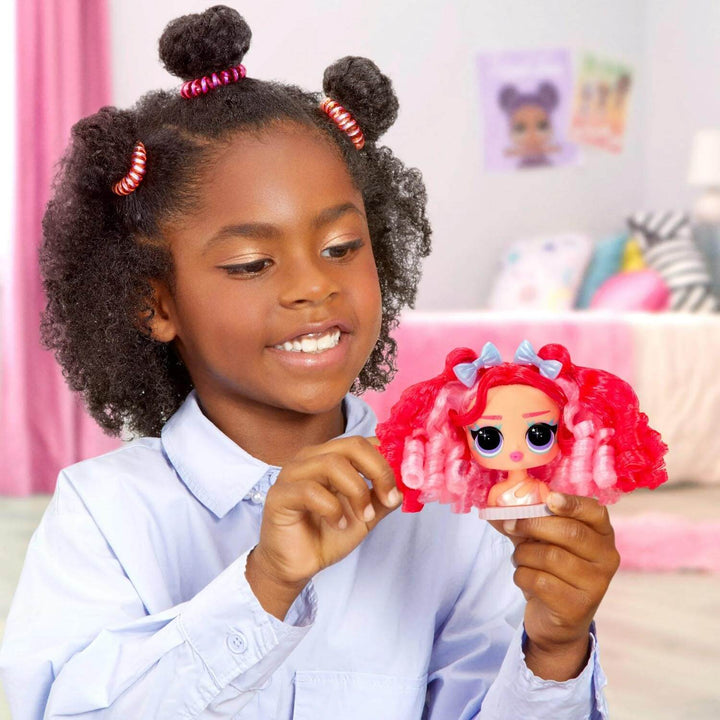 Child holding a doll with red hair and blue bows in a room with pink curtains.