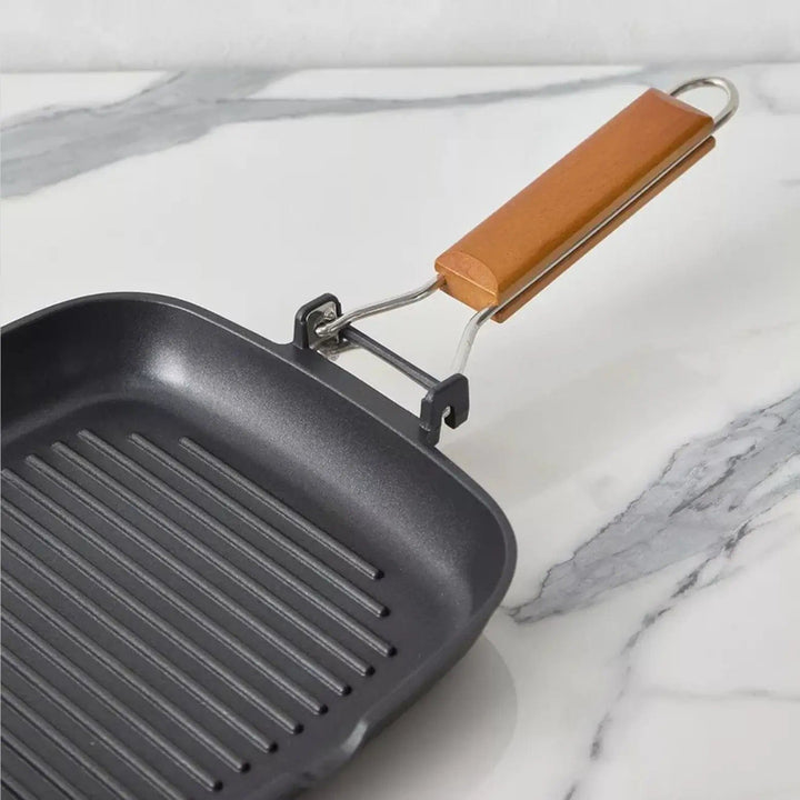 Close up of folding wooden handle on a grill pan with ridged surface
