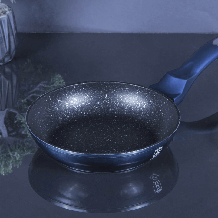 Black frying pan with speckled surface on a reflective surface in kitchen