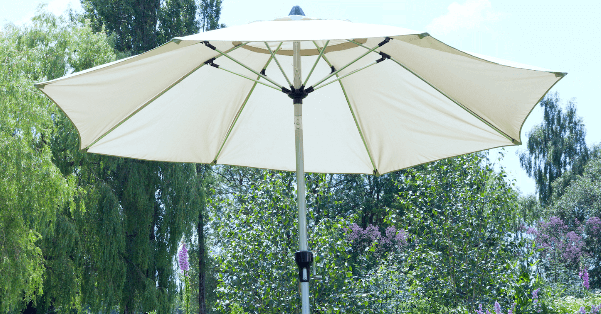 white coloured parasol in outdoor space with trees and lavendar plants in background