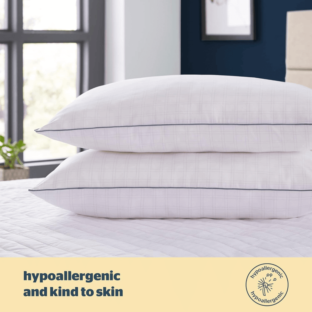 hypoallergenic and kind to skin details over image of 2 pillows piled on top of each other on white bed with blue wall in background