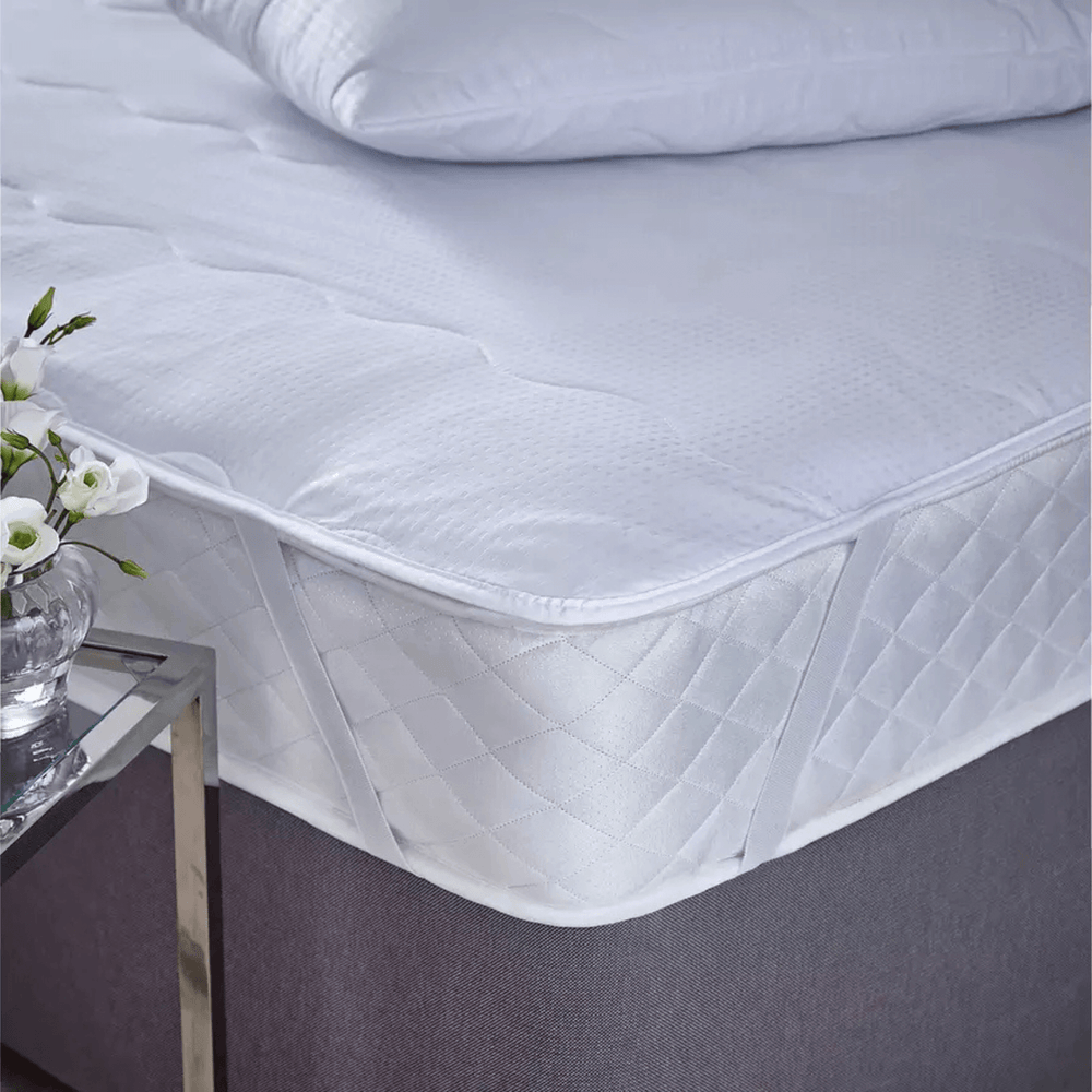 Mattress protector on a bed with flowers on side table