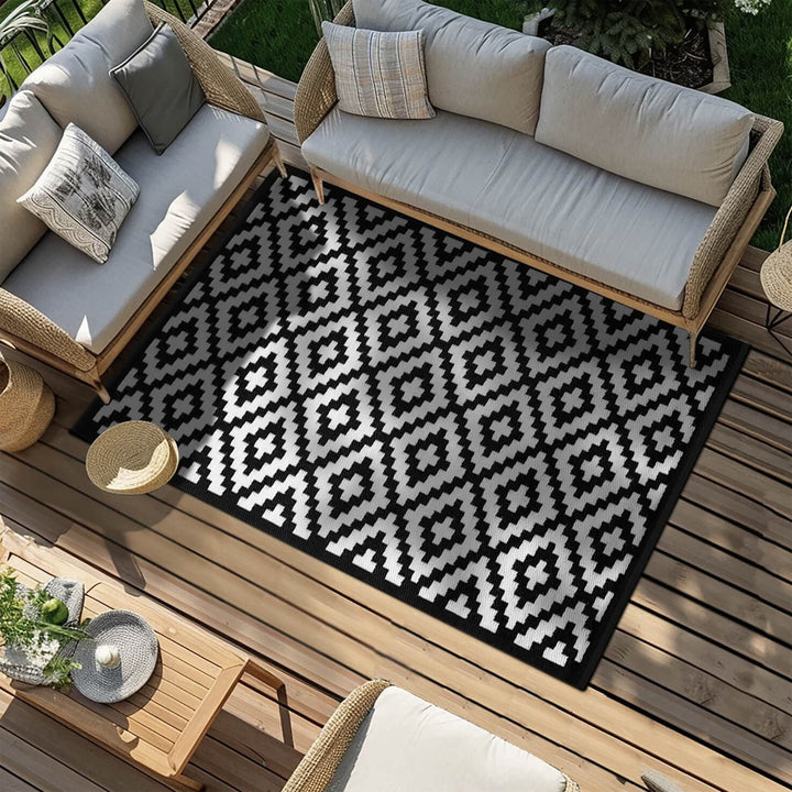 Black and white patterned rug on a wooden deck with outdoor furniture.