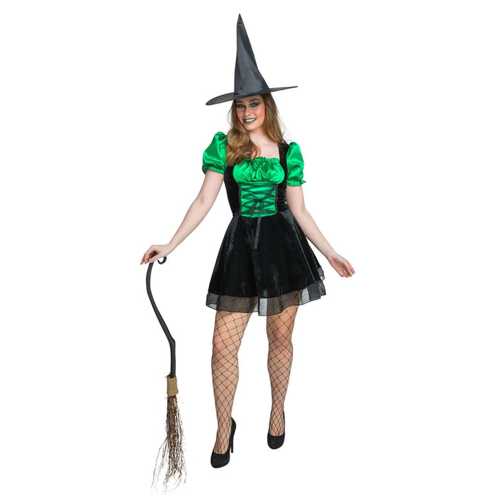 Woman in a witch costume with a green top and black skirt, holding a broom on a white background.