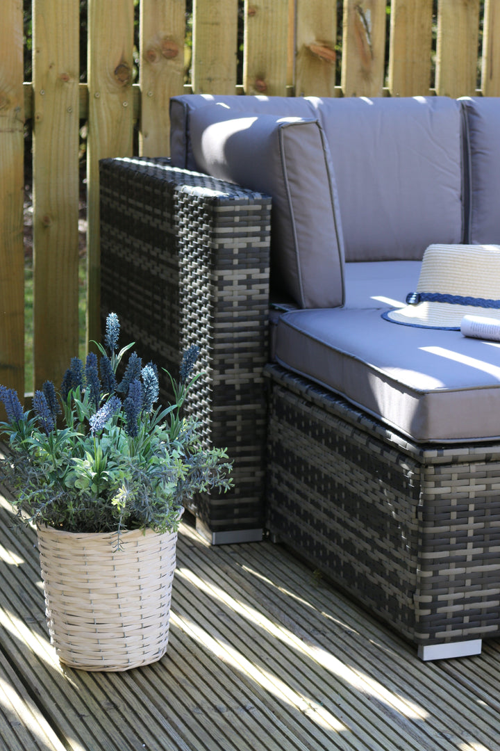 close up shot of dark grey rattan material on a patio space with lavender flowers in wicker pot sitting beside it
