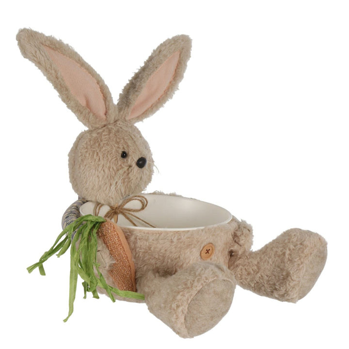 side view of plush rabbit with bowl and easter carrot on white background