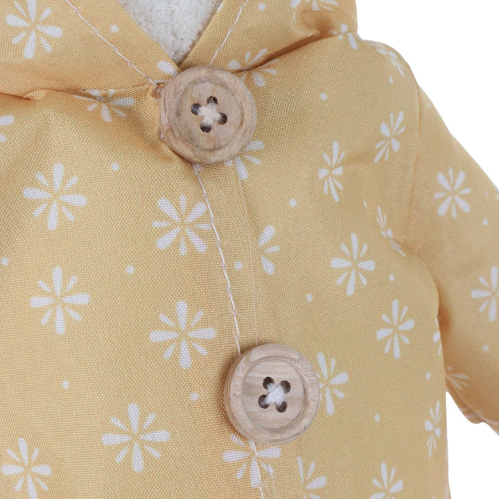 Close-up of a yellow fabric with white floral patterns and wooden buttons.