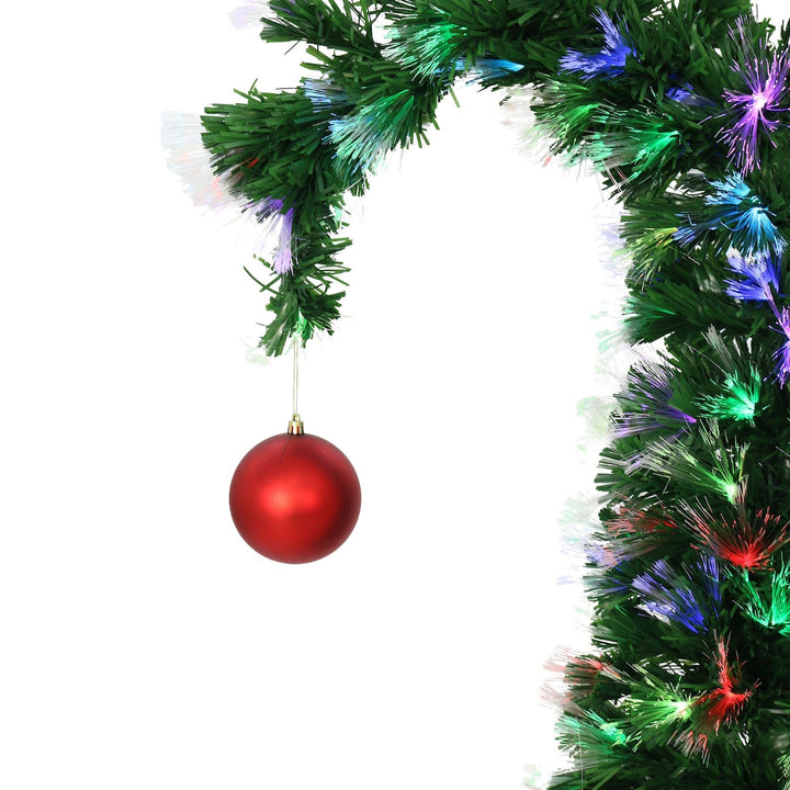 red bauble with gold string hanging on fibre optic christmas tree with multi colour lights