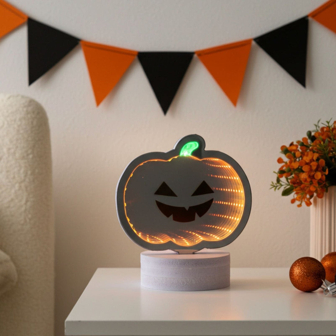 Pumpkin-shaped night light on a table with Halloween-themed decorations in the background.