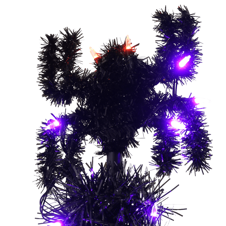 close up shot of tinsel spider at top of tree with purple and orange lights