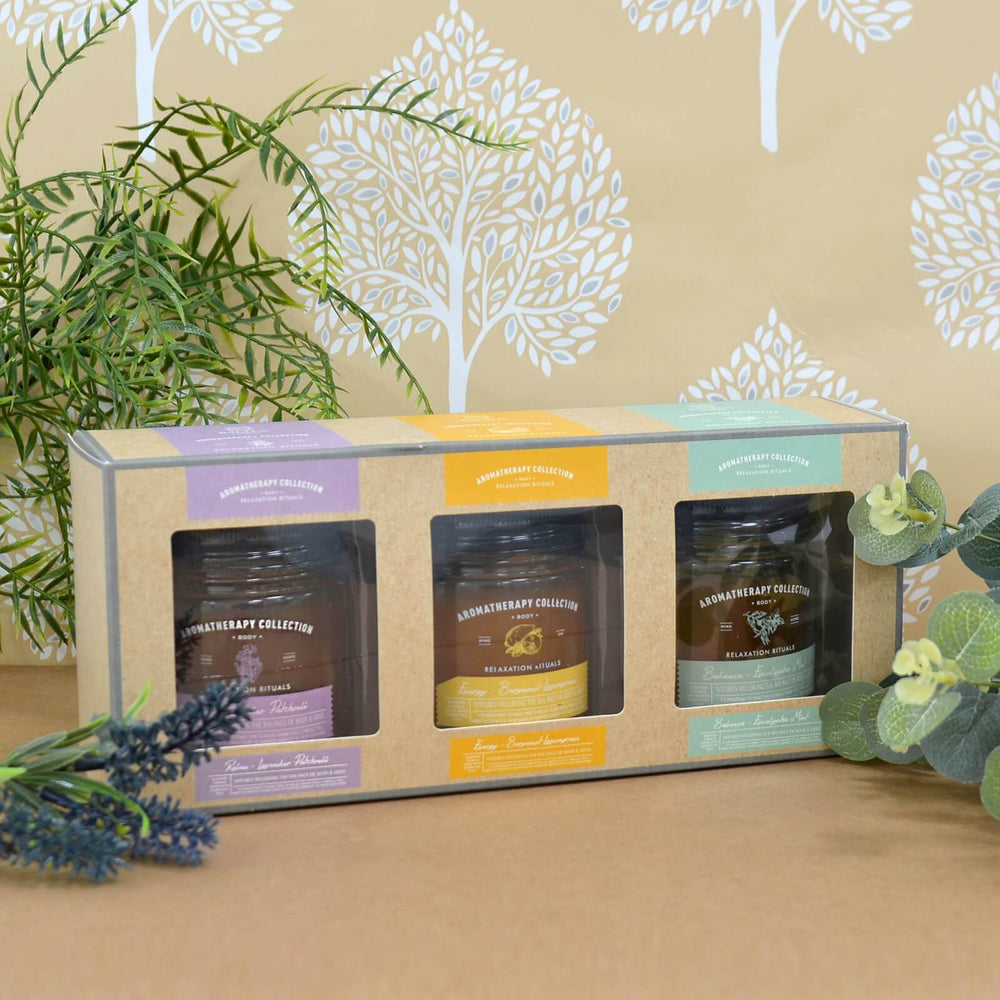 set of 3 aromatherapy candles on a brown coloured worktop with flowers to the front and side