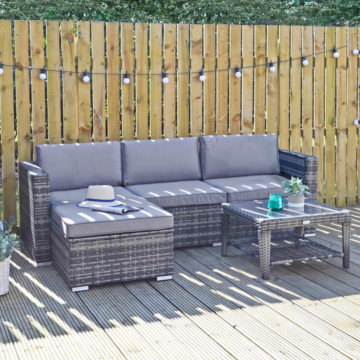 grey rattan monaco 5 piece sofa set on patio space with sun hat and magazine resting on grey cushions on ottoman