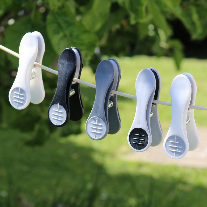 5 clothes pegs hanging on laundry line in sunny garden with trees and patio visible in background
