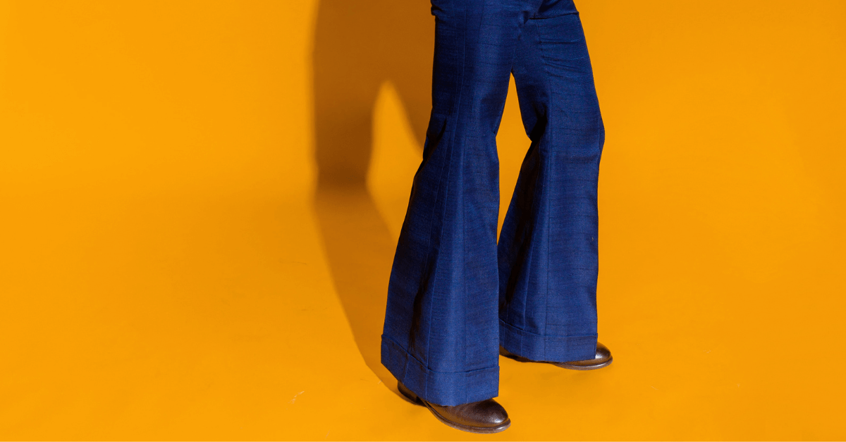 person wearing blue flared trousers on orange background
