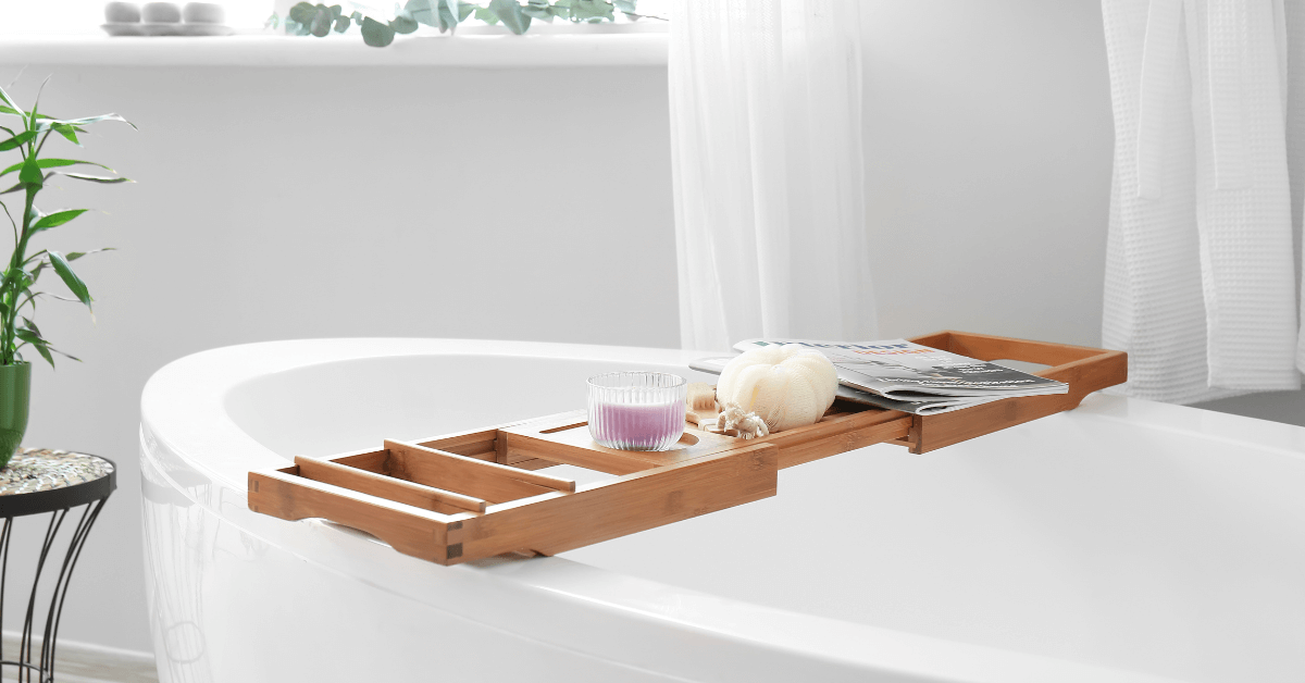 bamboo bath desk resting on white bath tub with candles and magazines resting on top
