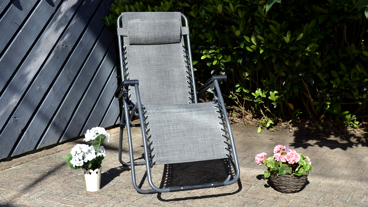 grey zero gravity relaxer chair on patio space with flowers to the side