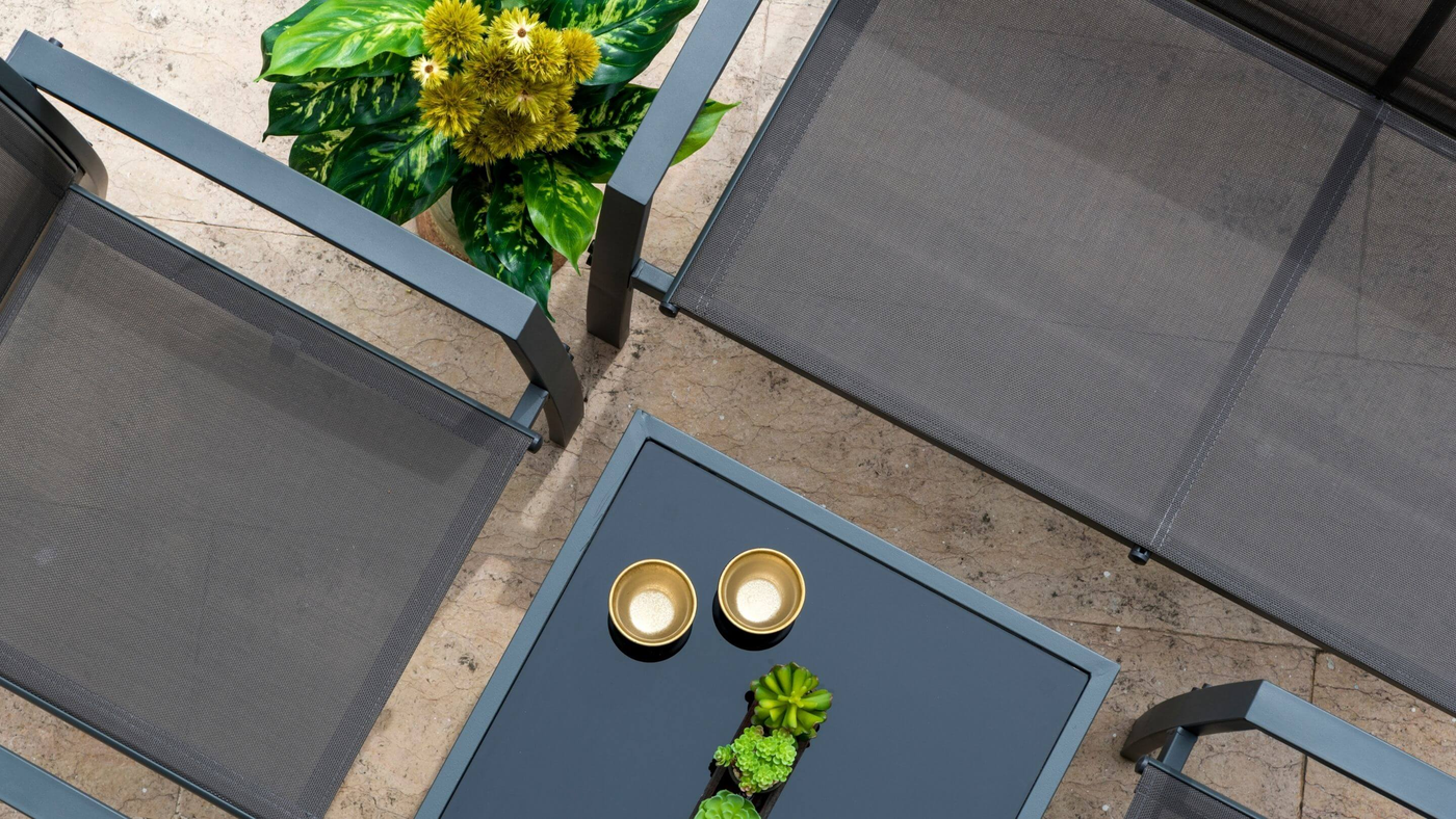 top view of black metal garden furniture with glass table top and decorated with plants
