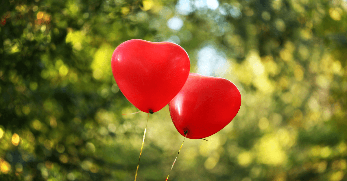 two red heart shaped balloons in outdoor location on sunny day