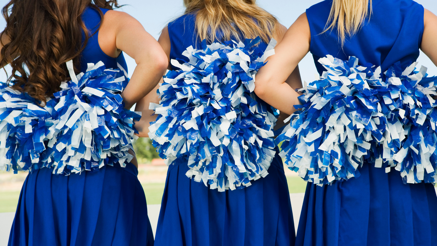 three chearleaders wearing blue cheer costumes with blue and white pom poms at their back